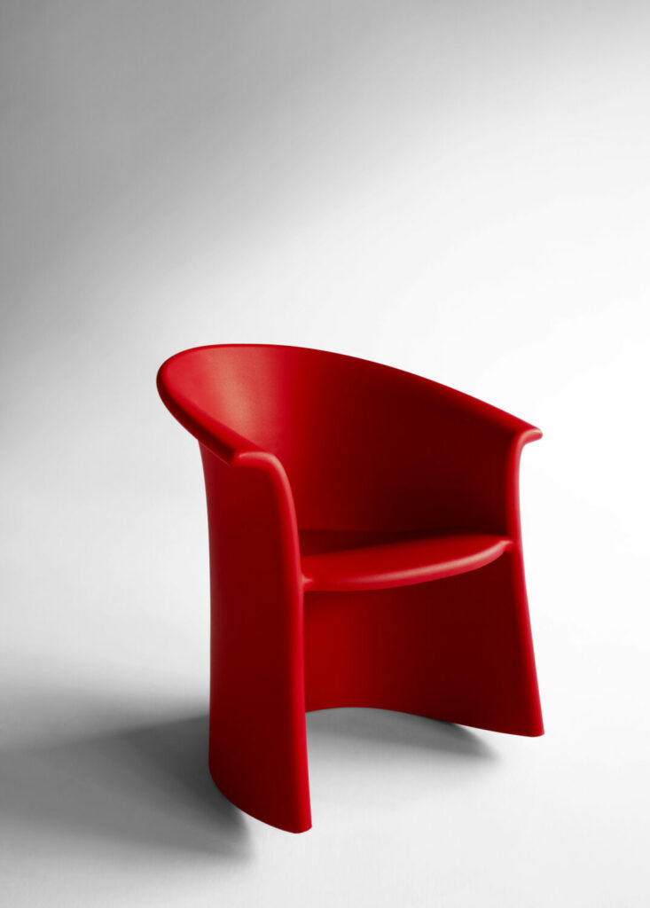 a red chair is the Vignelli Rocker NFT Sustainability Program by digby and Heller