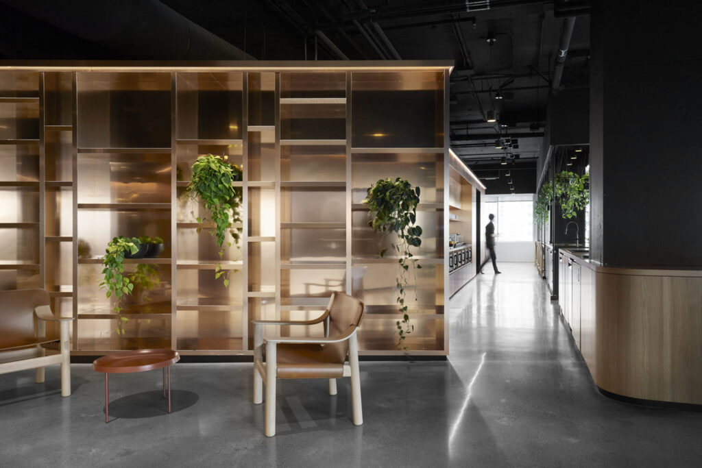 copper-toned shelving holds plants in front of a coffee table at the 2K office Montreal