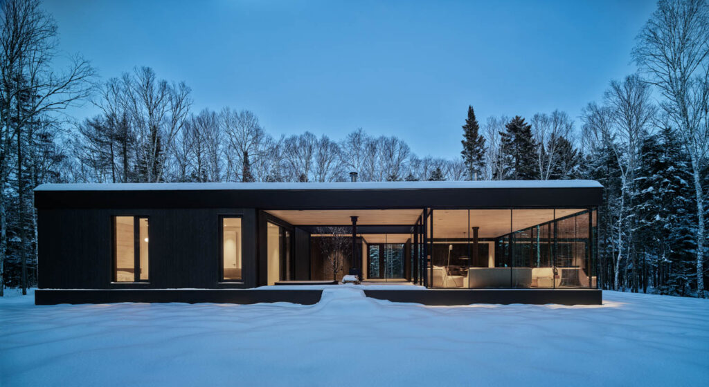 a house in Canada lit up at night atop a snowy landscape