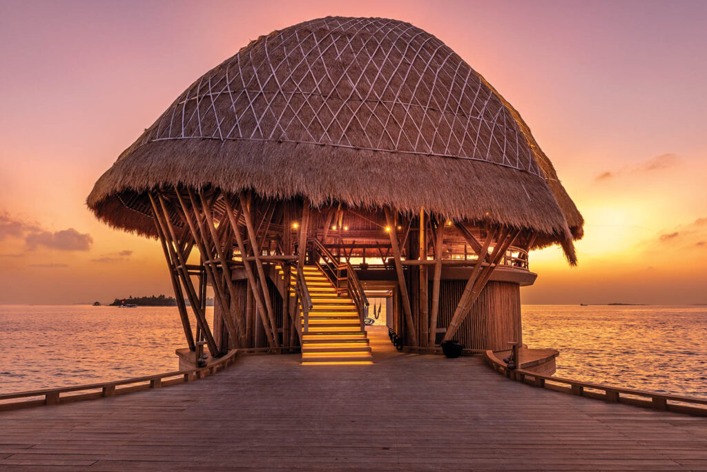 a hut covered dock at sunset