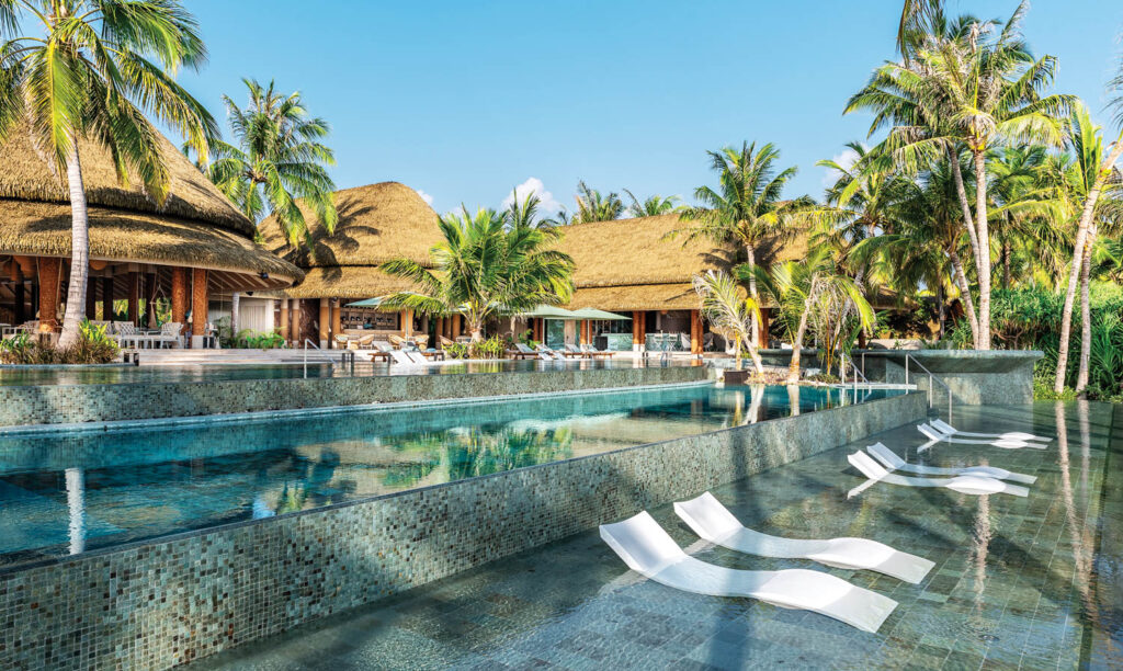the pool surrounded by palm trees at Joali Being