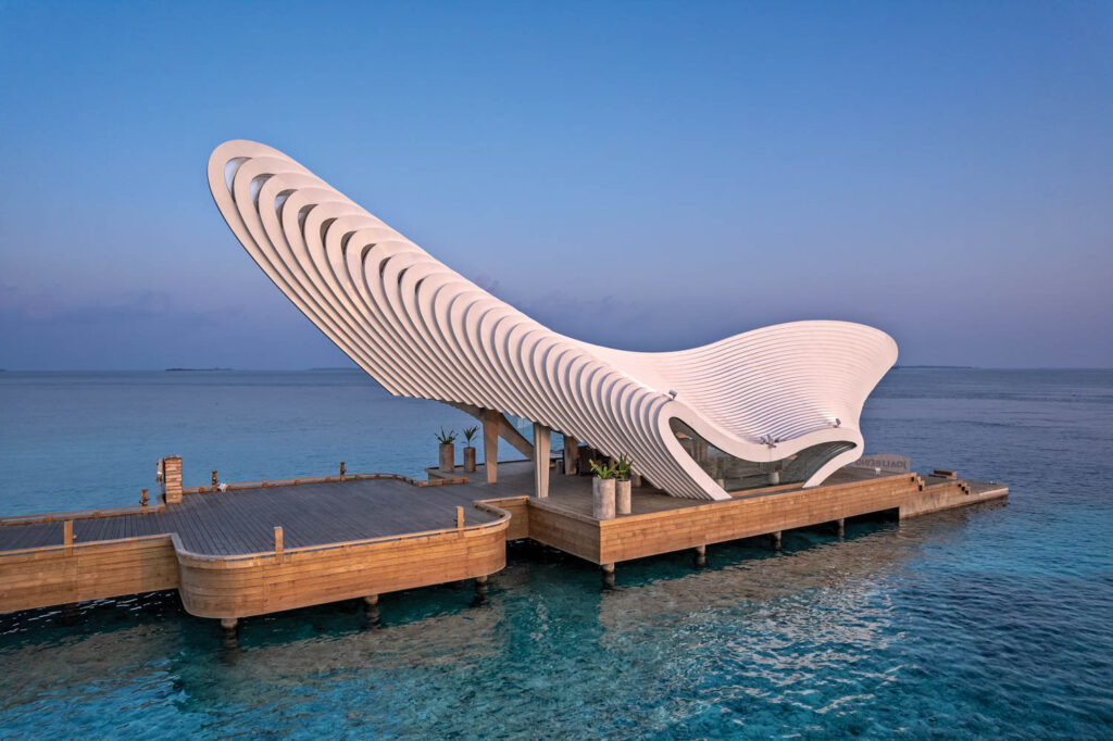 an arched covering goes skyward on a dock at Joali Being in the Maldives