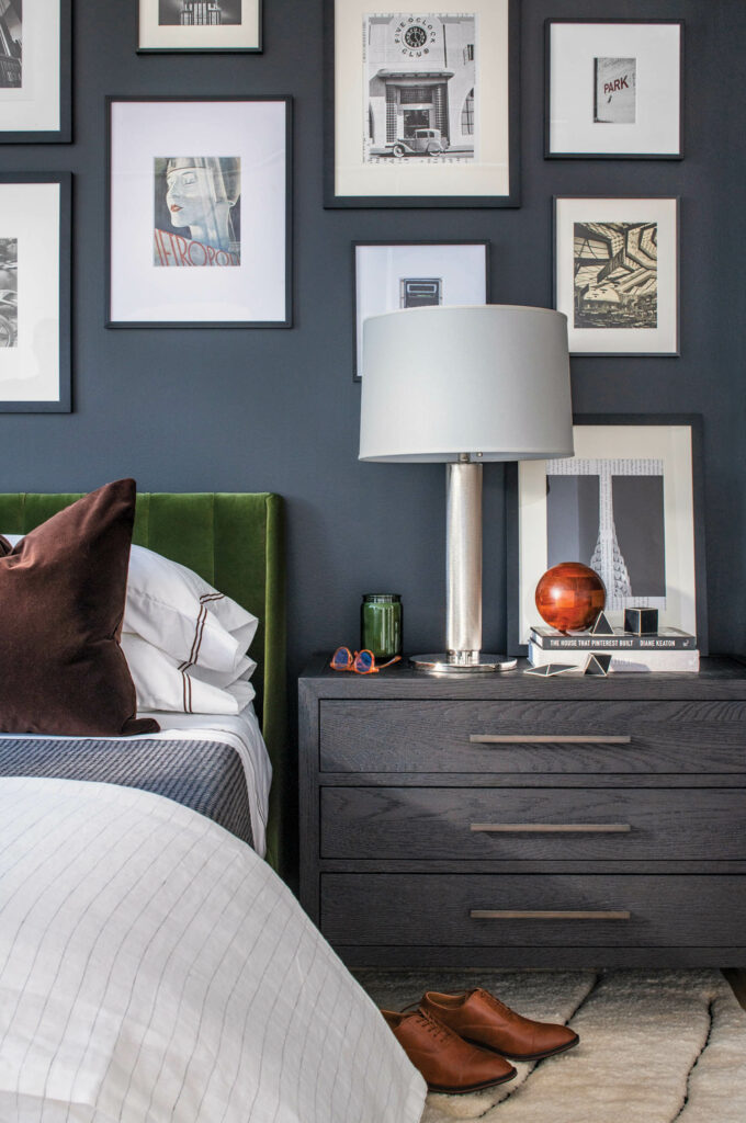 A bedroom with dark gray walls and a gallery wall of photos