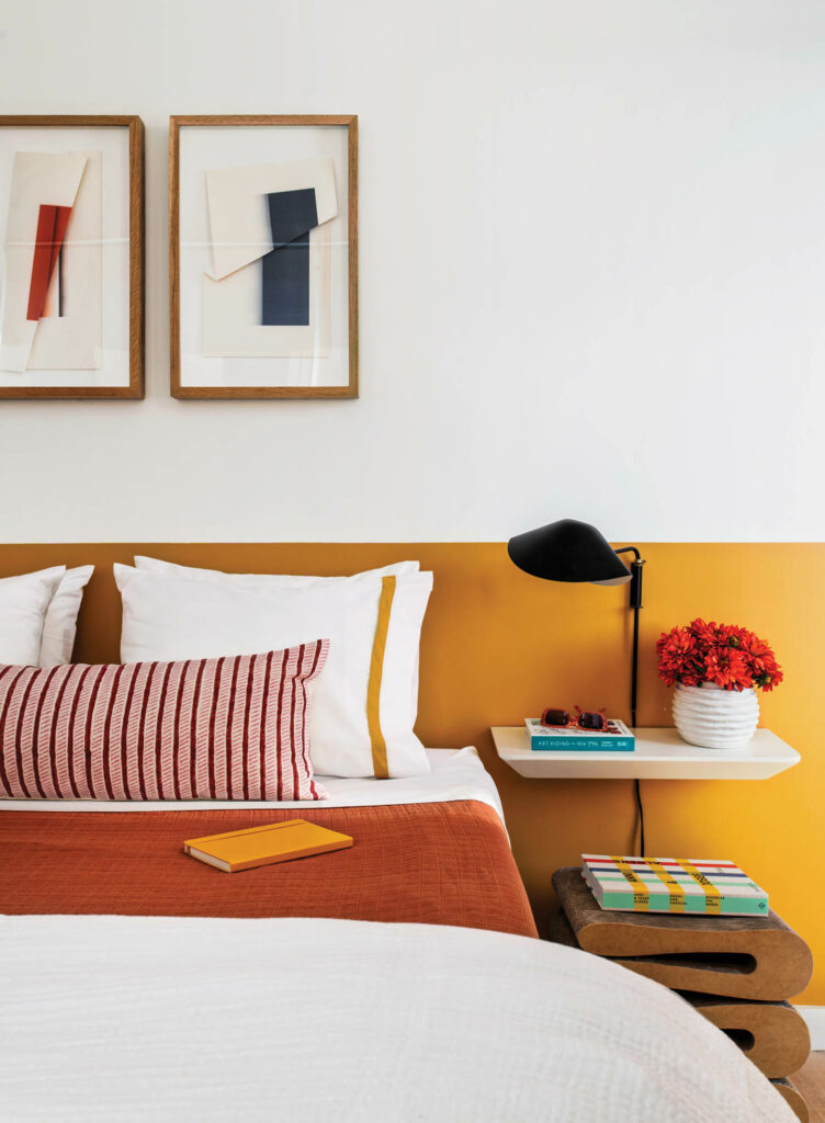 A bed with a yellow headboard and red striped pillows