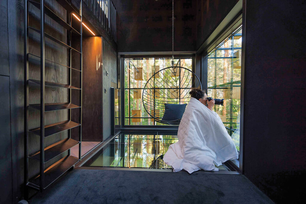 a photographer takes a photo out the window of a boutique hotel in the forest