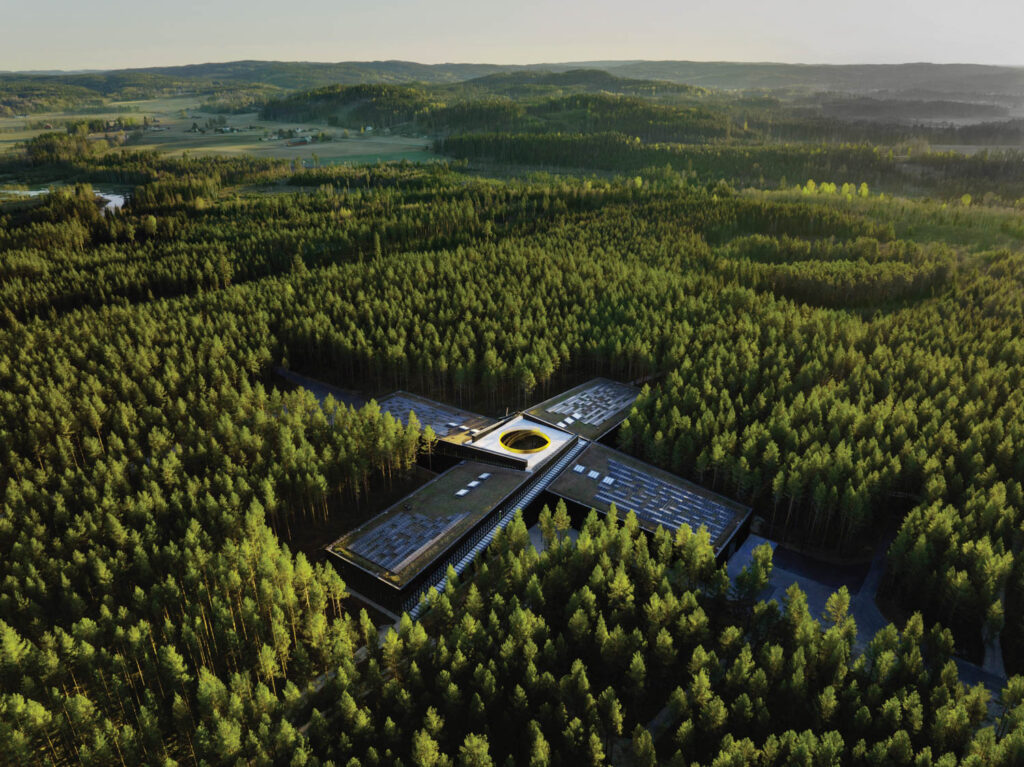An aerial view of The Plus, a plus sign building in the middle of a forest of trees