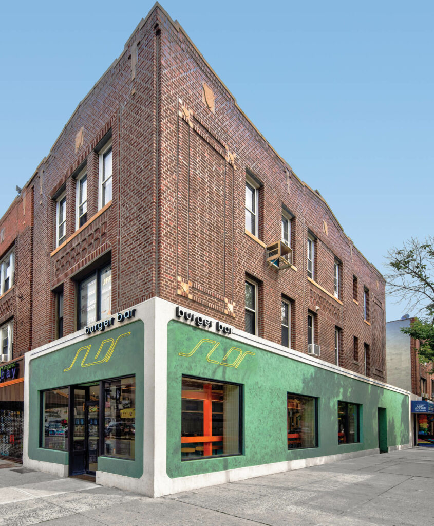 The exterior of the burger bar on the ground floor of a brick building includes a white border and a green facade