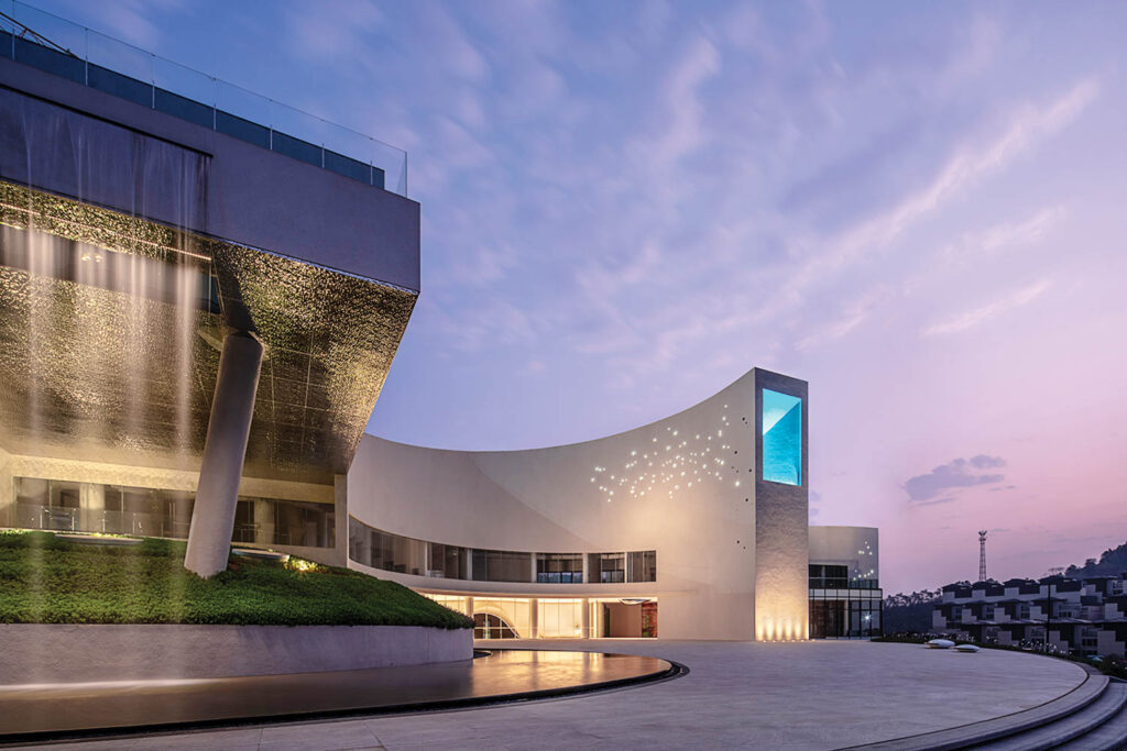 The library exterior shown at dusk with a pale purple sky mirrors the curves inside