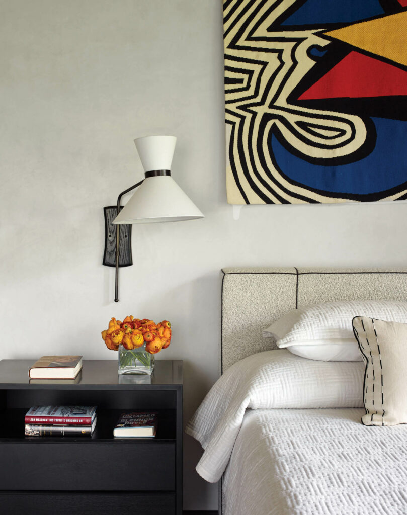 An Alexander Calder tapestry above a bed in a guest room