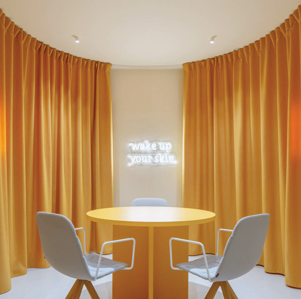 Orange curtains surround an orange round table with gray chairs