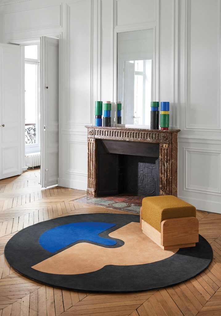 a round rug in black, yellow, and blue in front of a fireplace