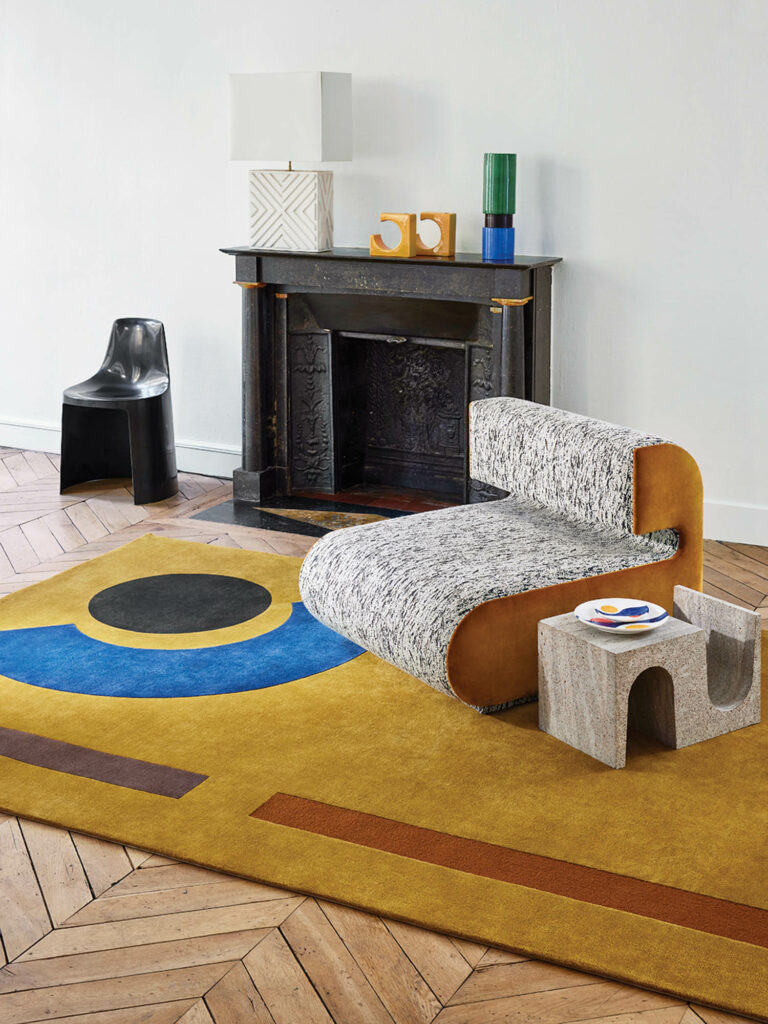 a rectangular rug in yellow, blue, and brown in front of a fireplace