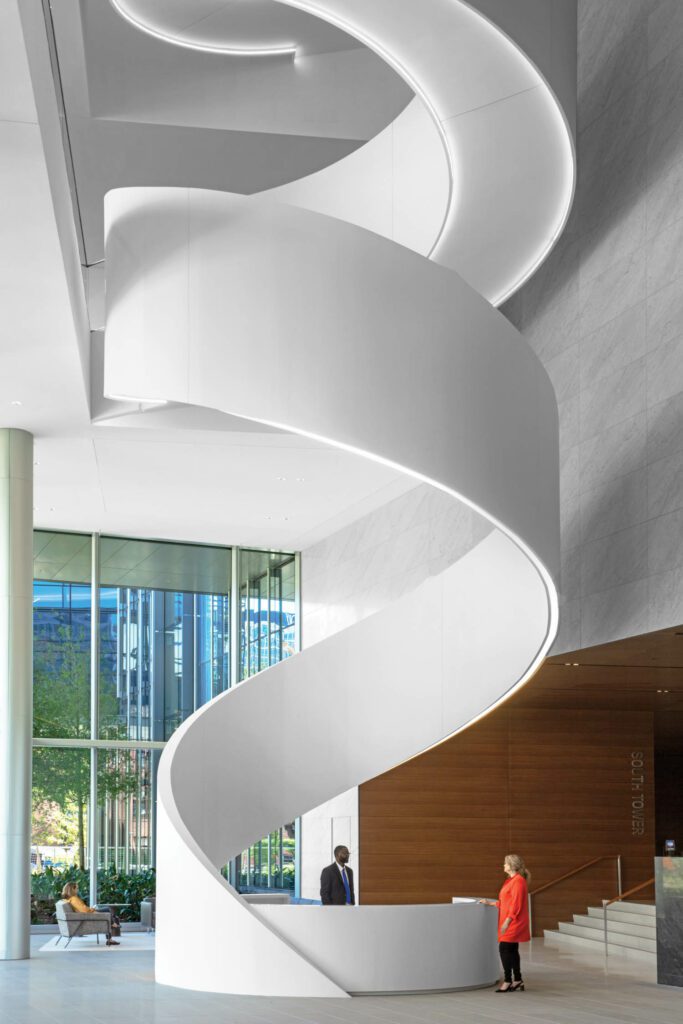 The stair’s Corian ribbon, with double LEDs on its underside, curls down to form the custom reception desk.