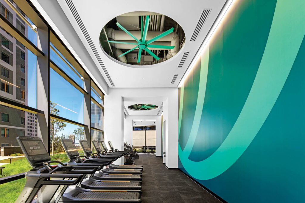 In the gym, ceiling fans are painted to match the custom digitally printed wall­covering.