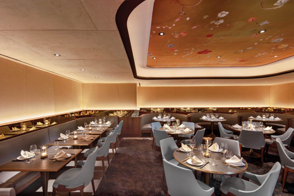 Above the room’s leather-upholstered seating, the ceiling recess hosts a mural by Candice Kaye Design. 