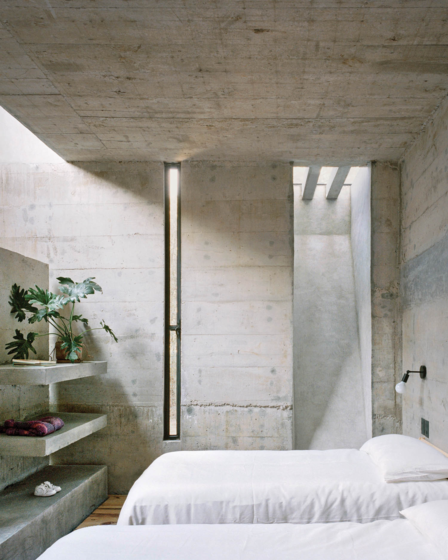 crisp white linens drape the beds inside a Brutalist bunker home, now a weekend retreat in Mexico
