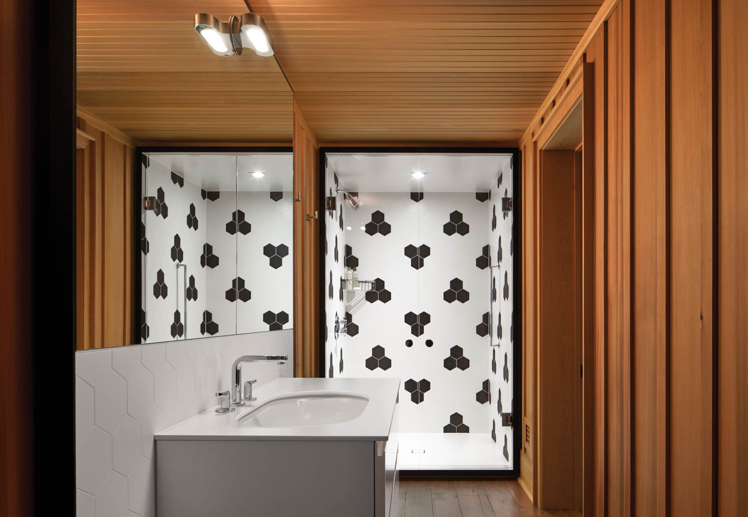 black and white hexagonal tiles line the shower of a bathroom