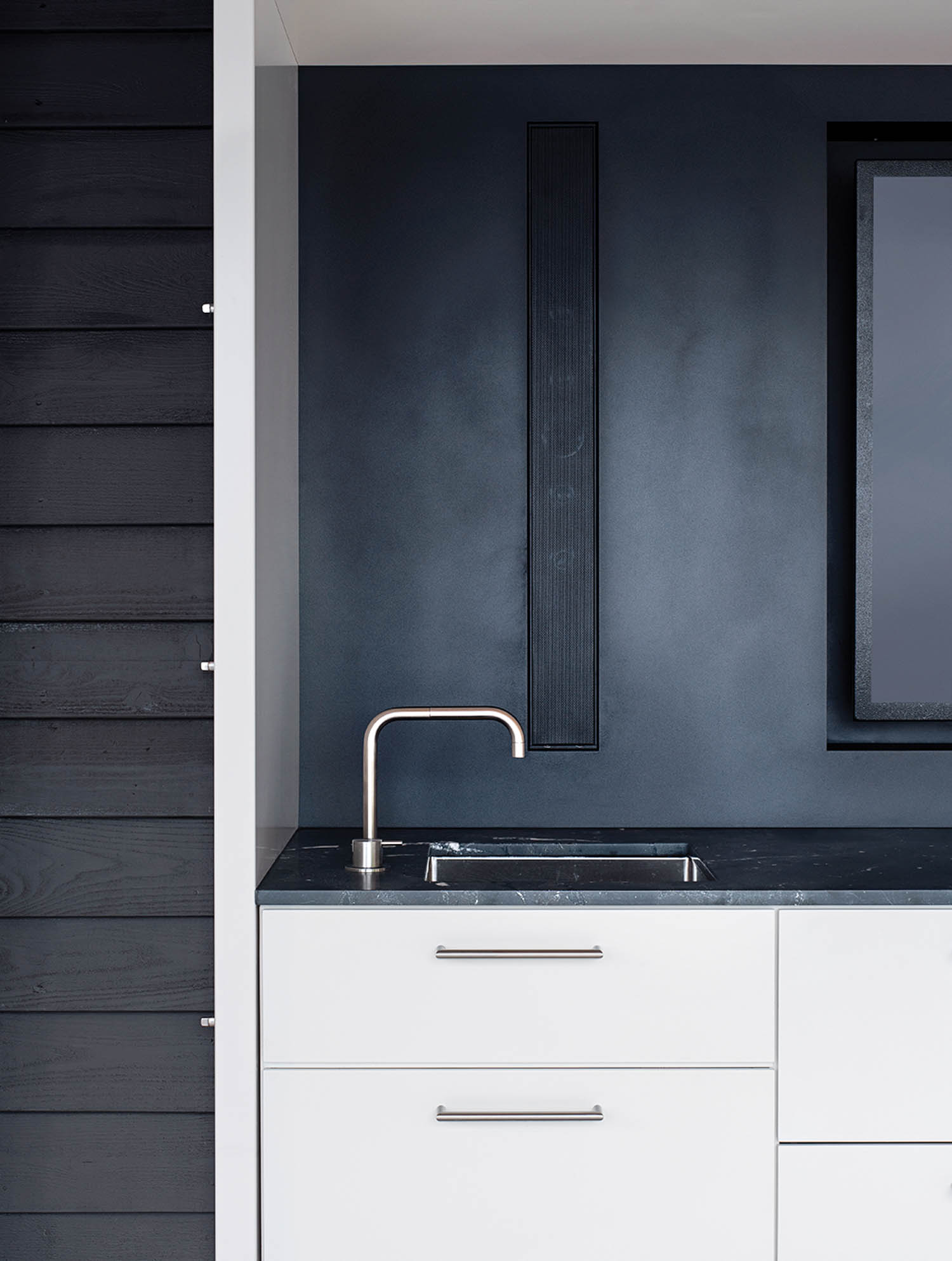a black wall above white cabinets in a kitchen