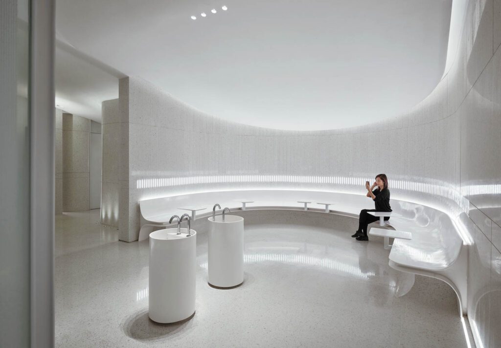 The bathrooms feature a monochromatic white palette with minimalist finishes like a curved bench.