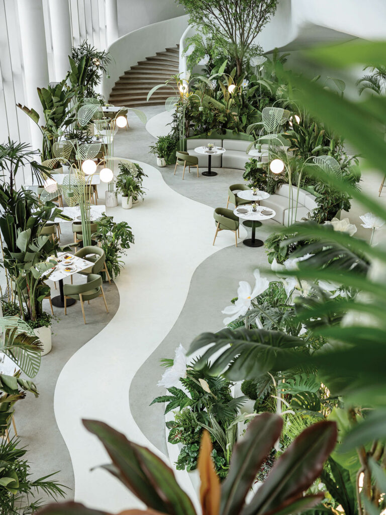 a pathway between greenery inside a dining area