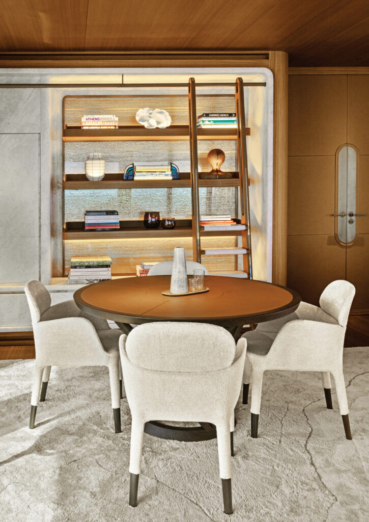 white chairs surround a table in front of a built in shelf in the living room of a yacht