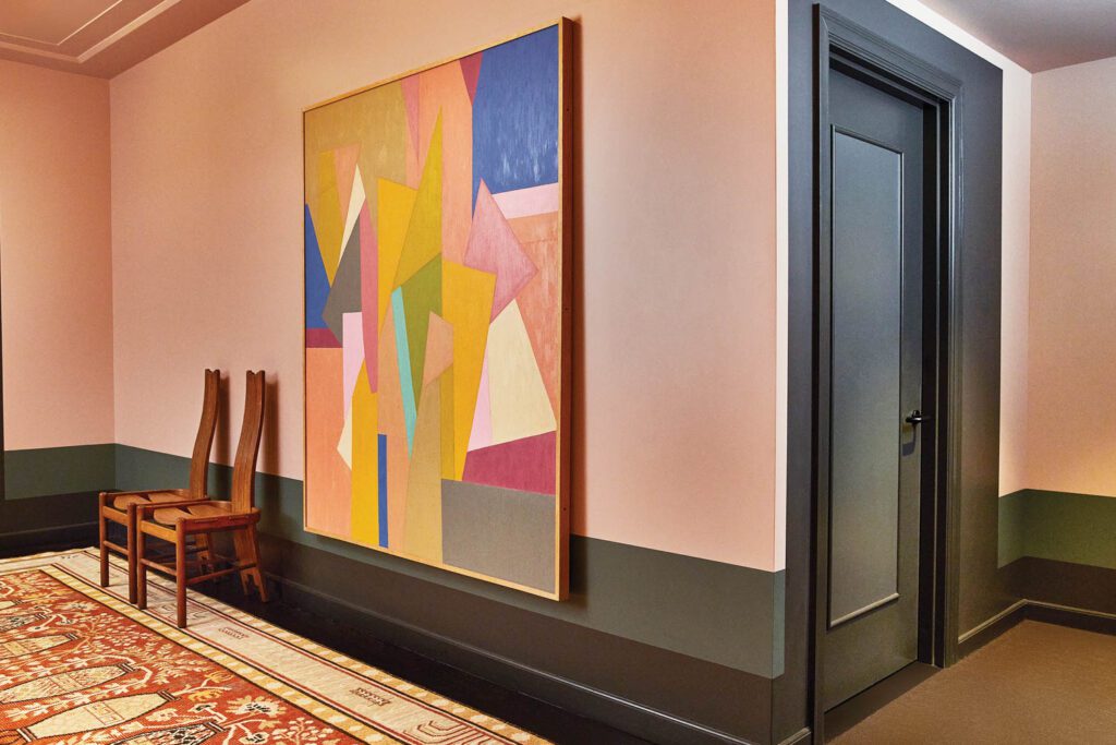 A custom woven rug and a vintage painting enliven a corridor.