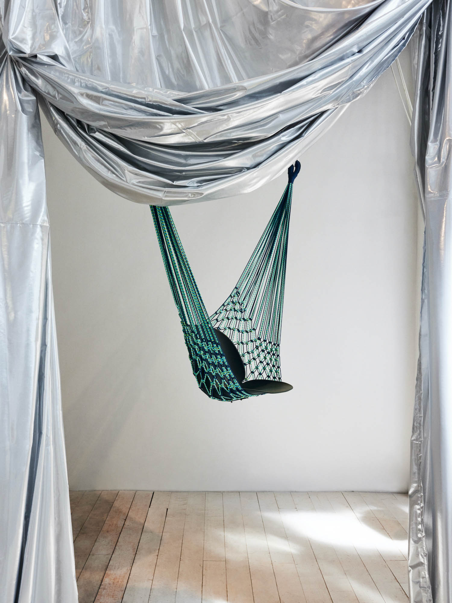 a chair hangs from a net in a Milan Design Week installation