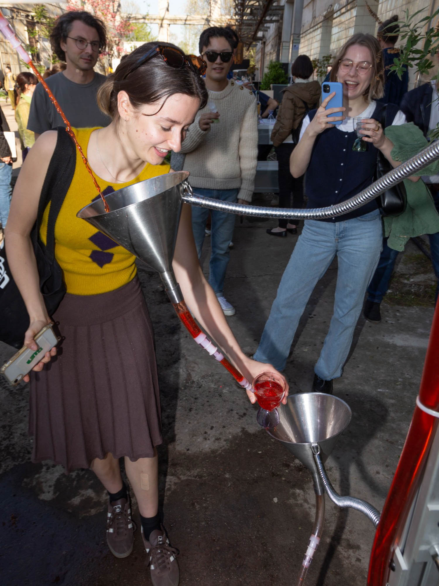 a woman pours her drink into a negroni fountain at Milan Design Week