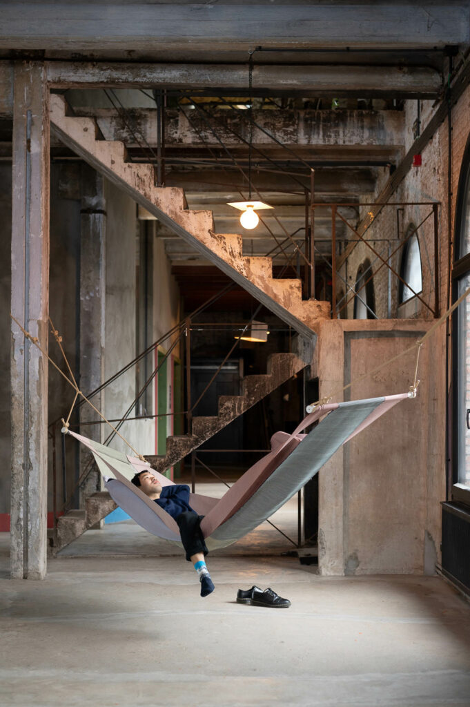 a person rests in a hanging bed that resembles a hammock