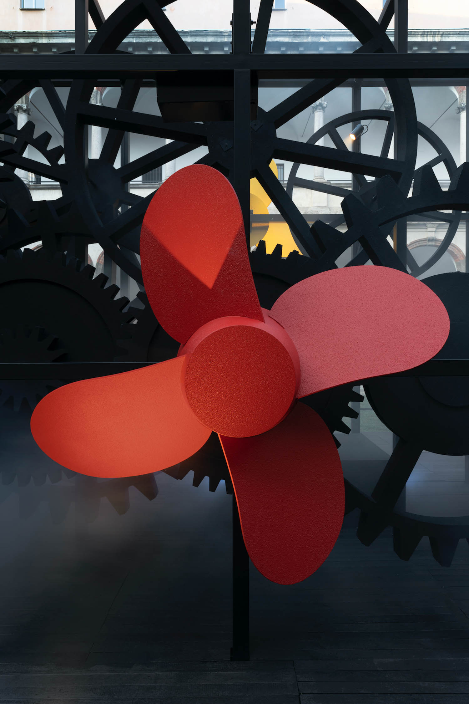 a red floral shaped propeller is part of a Milan Design Week installation