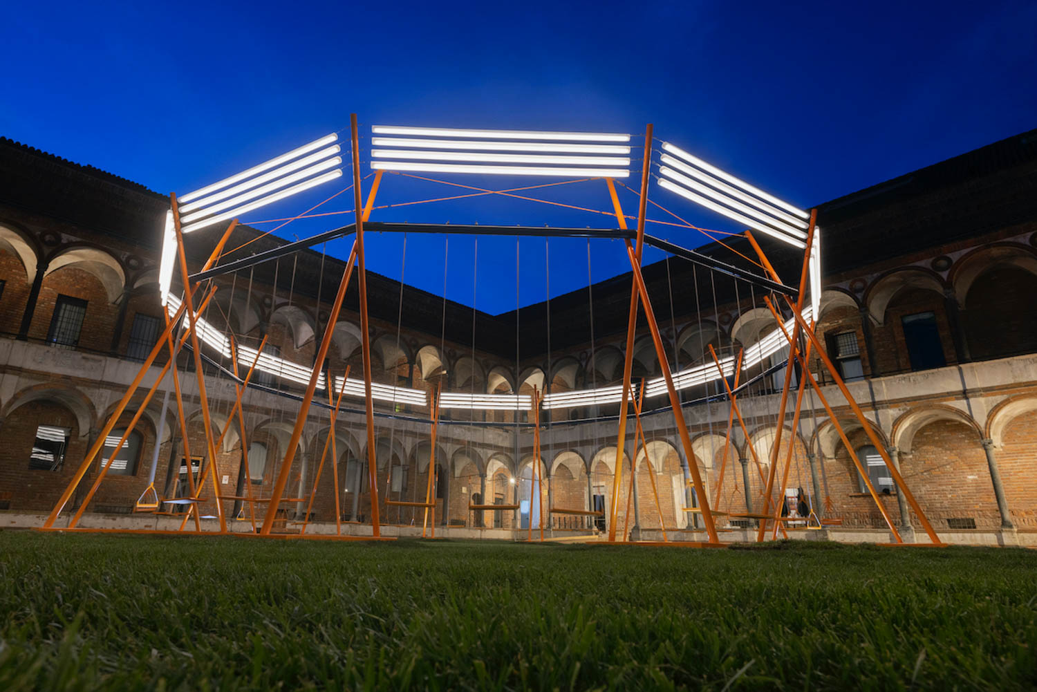 a supersized swing set is lit up at night at the University of Milan
