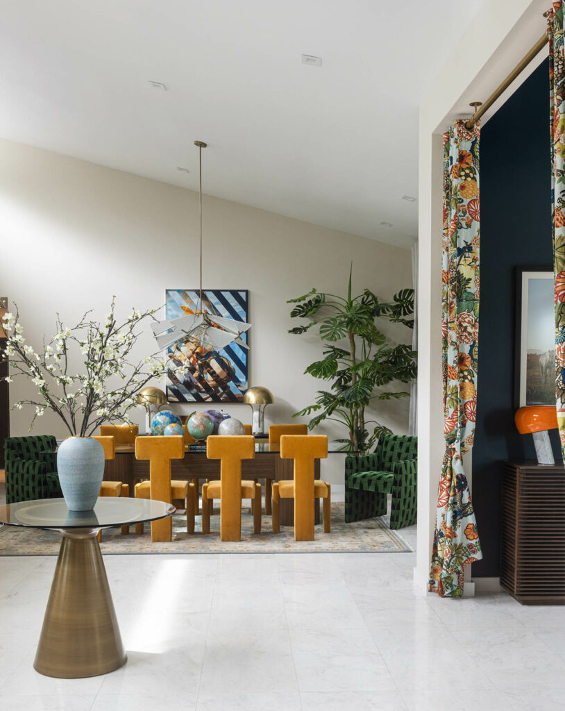 A maximalist dining room with a table surrounded by orange chairs in a geometric pattern