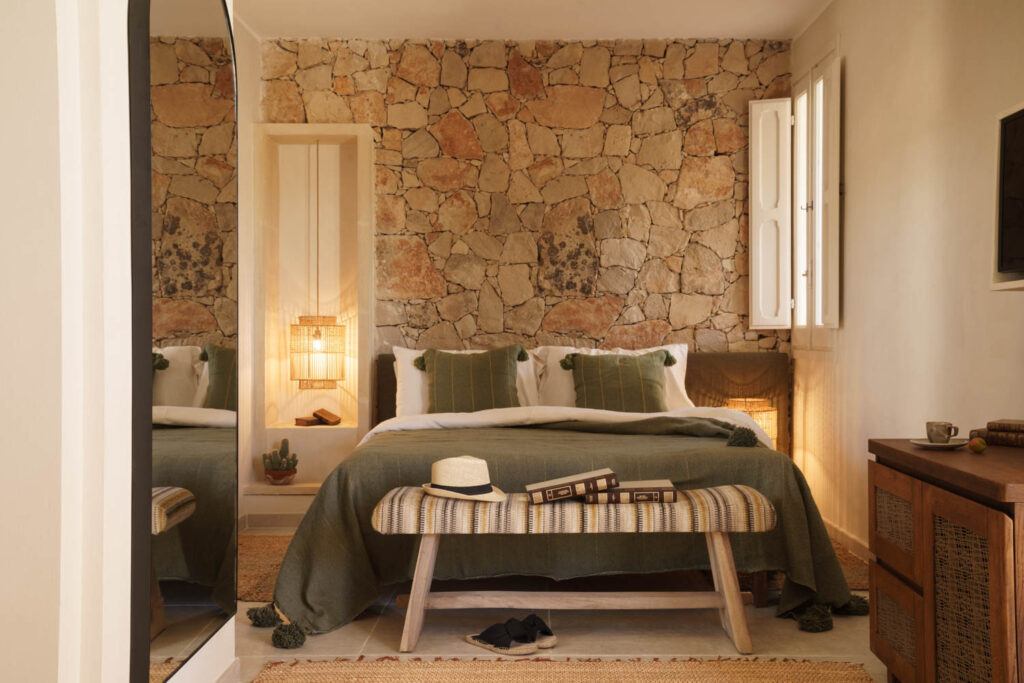 a stone wall behind the bed in a guest room at an Italian boutique hotel