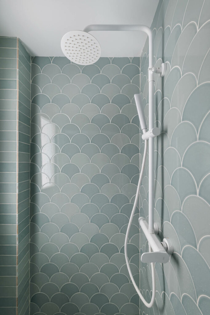 The bathroom features turquoise tiles with a glossy finish to reflect the light.
