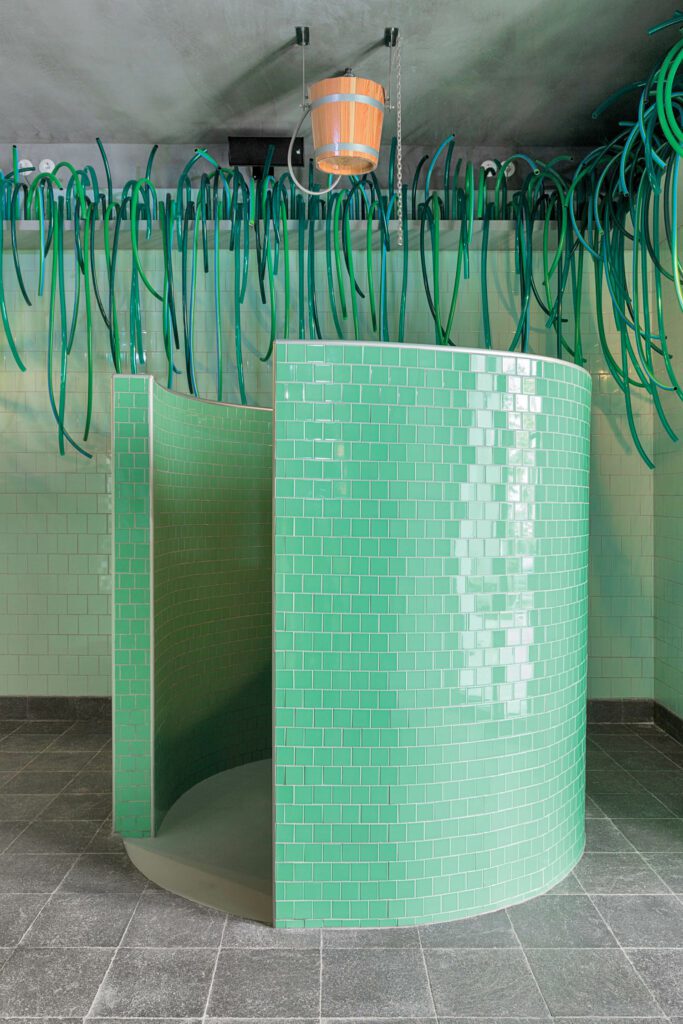Ceramic tile clads the circular bucket shower in the sauna.