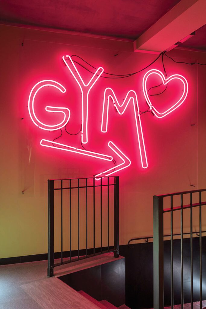 A custom neon sign points the way to the basement gym.