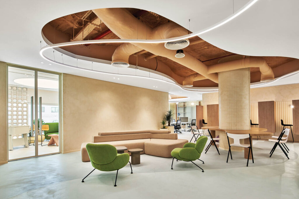 a lounge area with brown sofa and green accent chairs creates an inviting space for guests in the Abu Dhabi office