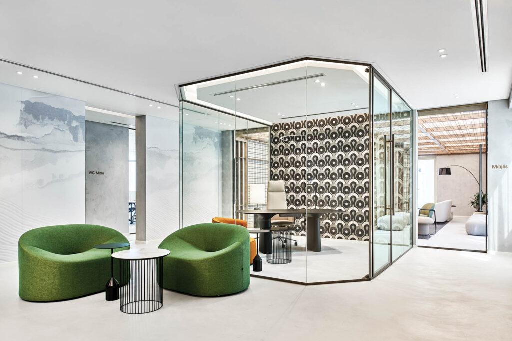 a glass-enclosed office flanked by green lounge seating