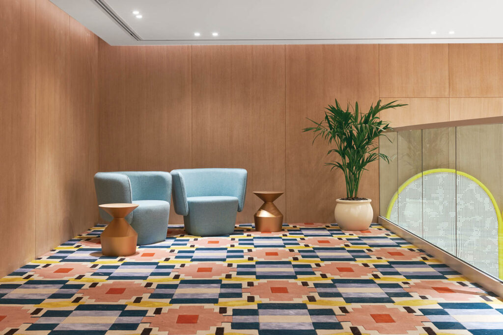 a room with geometric patterned carpet with blue accent chairs