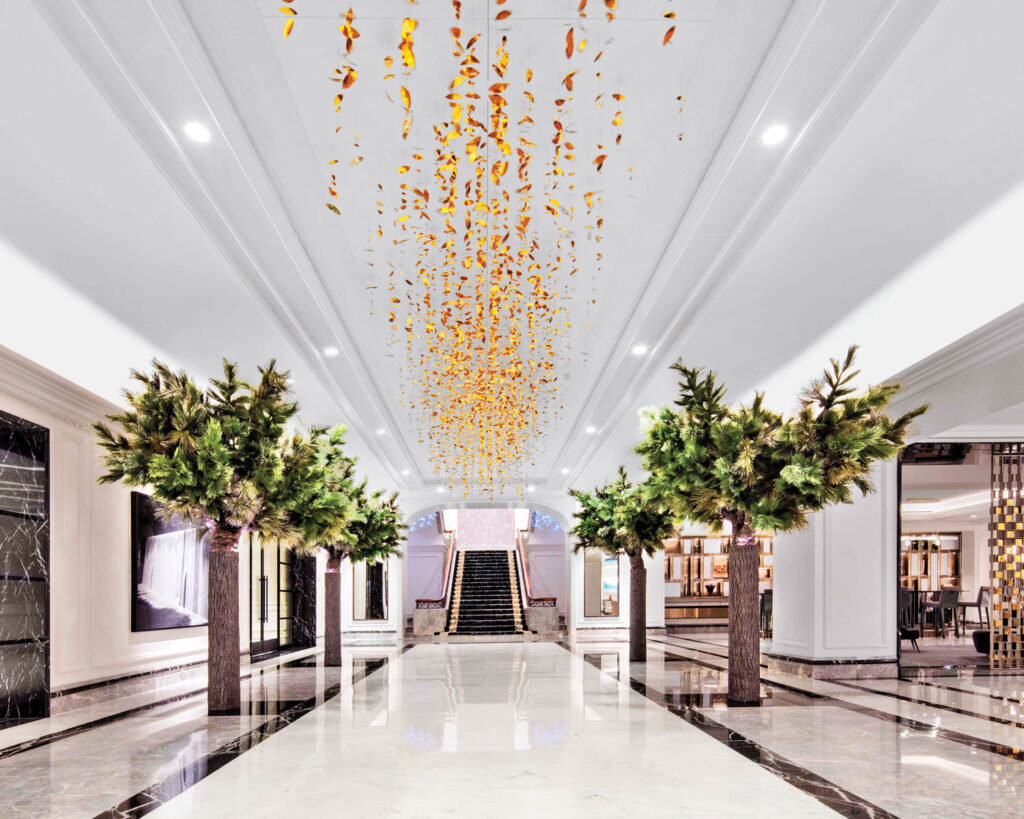 an installation of gold-tinted aluminum hangs from the lobby ceiling of a Four Seasons hotel