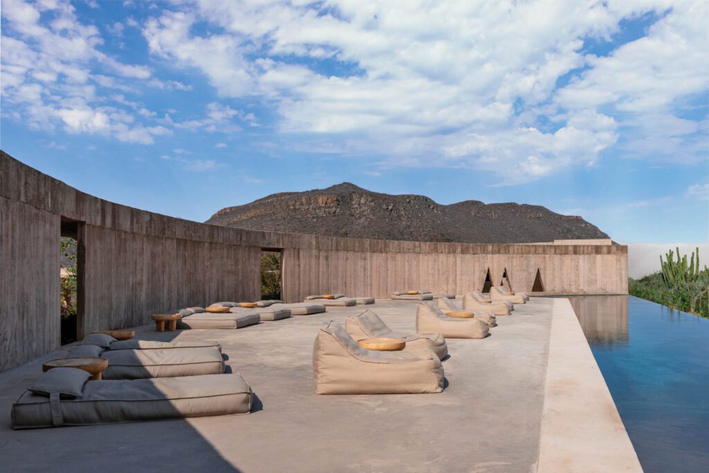 At Paradero Todos Santos, a new 35-room resort and spa in Baja California Sur, Mexico, by Rubén Valdez, Yashar Yektajo Architects, and interior design studio B-Huber, a half-moon pool deck of poured-in-place concrete embraces the surrounding landscape.