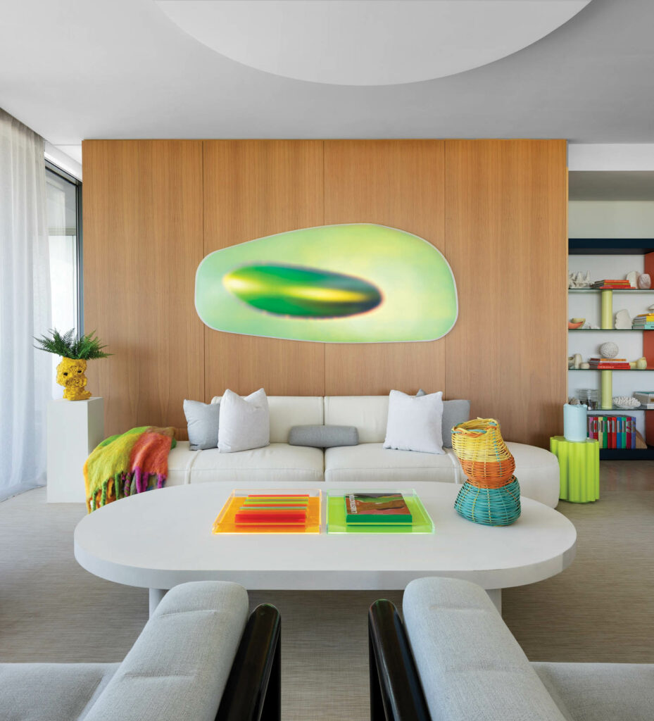 a neon green artwork on the wall above a white sofa and coffee table