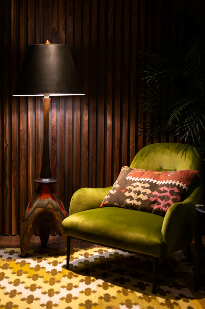 a vintage floor lamp next to a green chair in the nook of the VIP lounge at Superstition