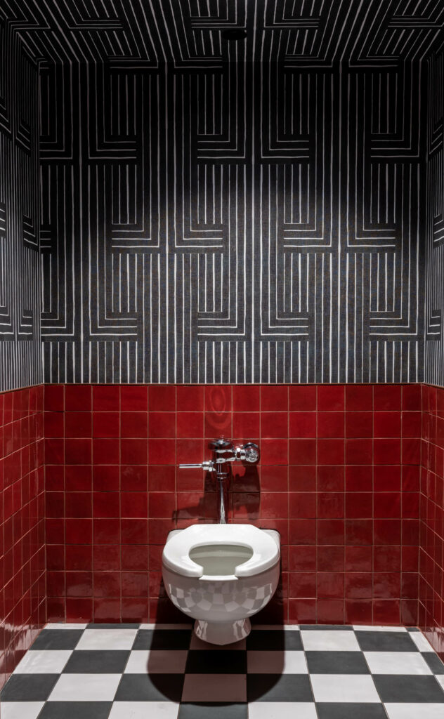black and white wallcoverings meet red tile in a night club bathroom