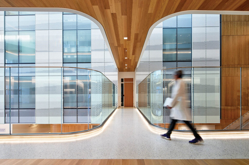 a clinician walks through a hallway lit by natural light from large windows